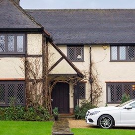 Outdoor view of a old house with vines growing outside and a car parked outside
