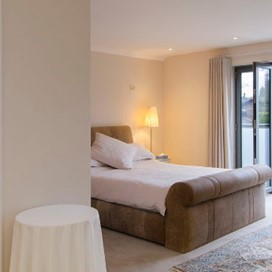 A double room with ensuite, rug and doors opening out onto a Juliet balcony