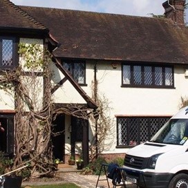 White car parked outside of a old country cottage fitted with origin windows 