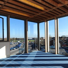 Looking into the corner of the room and out through large windows over a car park