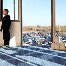 A view from the inside of a room with children sat in front of a floor to ceiling window