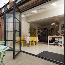 Side view from the outside of a modern dining room with a open set of bifold doors