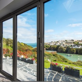 Looking through white bifold doors onto a large bright garden