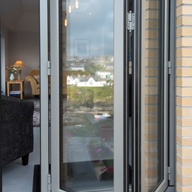 Open set of white bifold doors from the outside looking into a modern living room