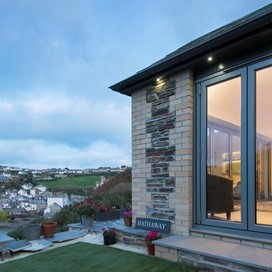 Outside view of a home fitted with bifold doors looking over a night time landscape