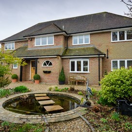 An exterior shot of the house looking over a pond with stepping stones - showcasing Origin's windows