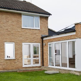 A view from the lawn at the back of a house with an extension featuring a large corner door