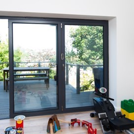 A bright room with partially opened folding doors looking out onto upper storey decking