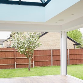 Looking out of a garden room through open folding doors that cover two walls