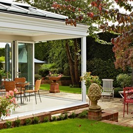 The view from the garden of a beautiful garden room, with folding doors fully opened up