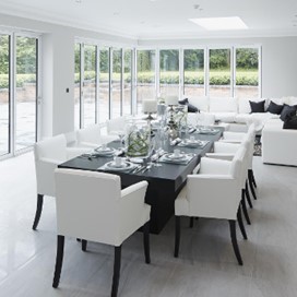 A bright dining area with large bifold doors and a corner door covering the length of the room