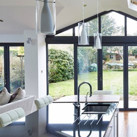 A large, bright, open plan kitchen and living area with large glass folding doors leading out to the garden