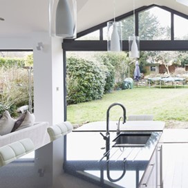 A large, bright, open plan kitchen and living area with large glass folding doors opening out to the garden
