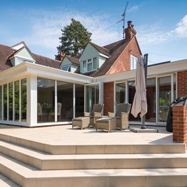 Side outside view of large house looking into the garden showing off white bifold doors