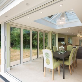Inside of extension showing a set of chairs around a table with a open bifold door behind