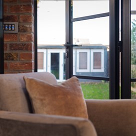 Cream chair in the corner of the room looking out through bifold doors to a garden