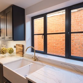 Kitchen sink below a kitchen window with sun shining through