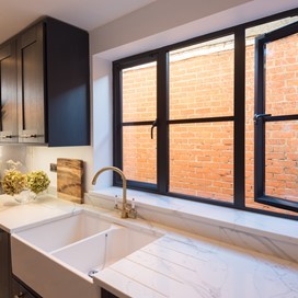 Kitchen sink below a kitchen window with sun shining through