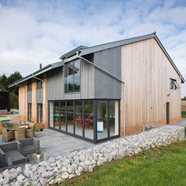 Side shot of barn conversion with black bifold doors looking over the garden