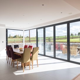 Indoor dining set of table and chairs overlooking garden through set of bifold doors