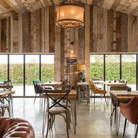 Dining hall looking out onto a farm through bifold doors 