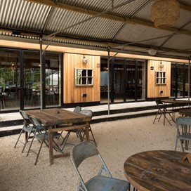 Outdoor dining tables sheltered by umbrellas placed on the outside of the bifold doors