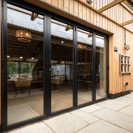Black bifold doors closed from the outside looking into the dining hall