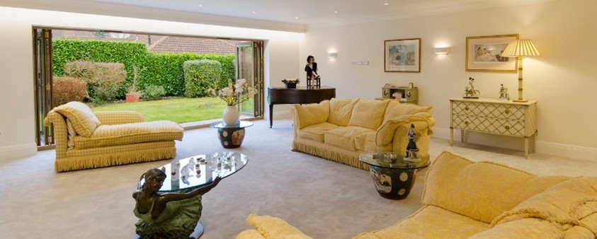 A large lounge with fully open bifold doors looking into the garden