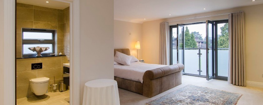 A double room with ensuite, rug and doors opening out onto a Juliet balcony