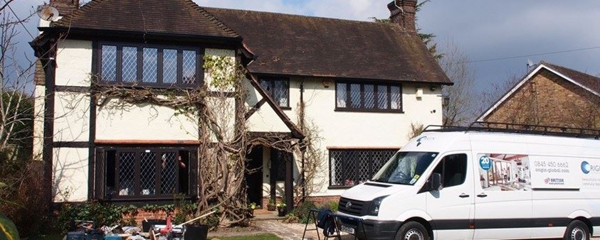 White car parked outside of a old country cottage fitted with origin windows