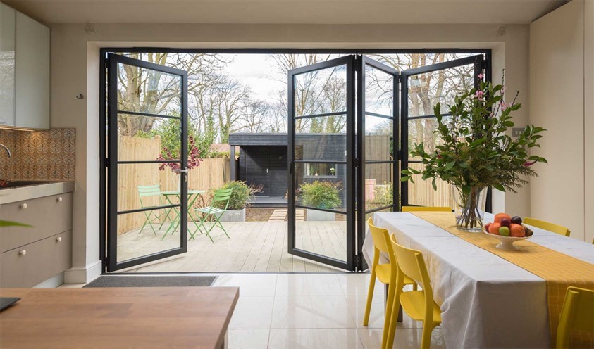 View from a dining room looking out into a garden through open bifold doors