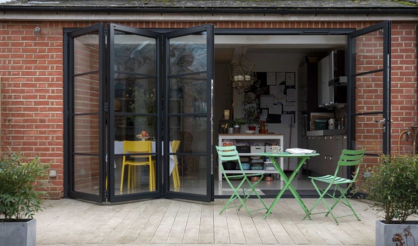 Outside looking into a modern dining room, looking through open bifold doors