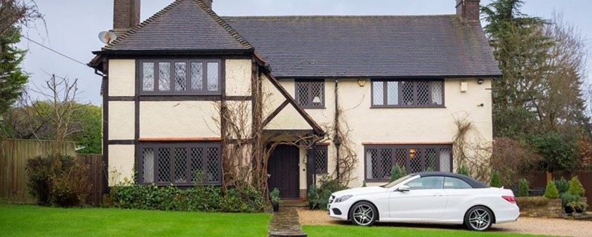 Outdoor view of a old house with vines growing outside and a car parked outside