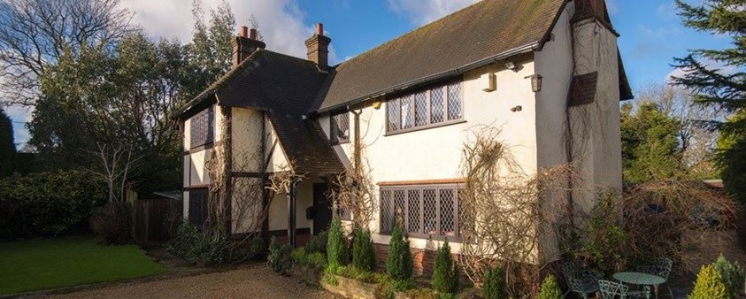 Side view of old cottage house with bush running below the window