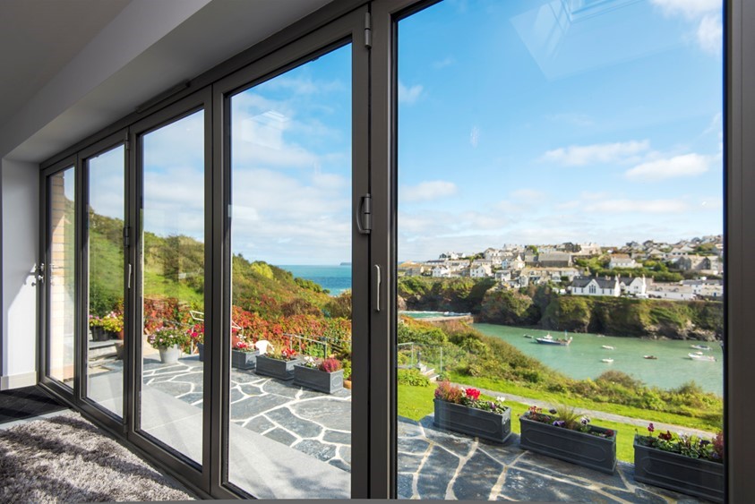 Looking through white bifold doors onto a large bright garden