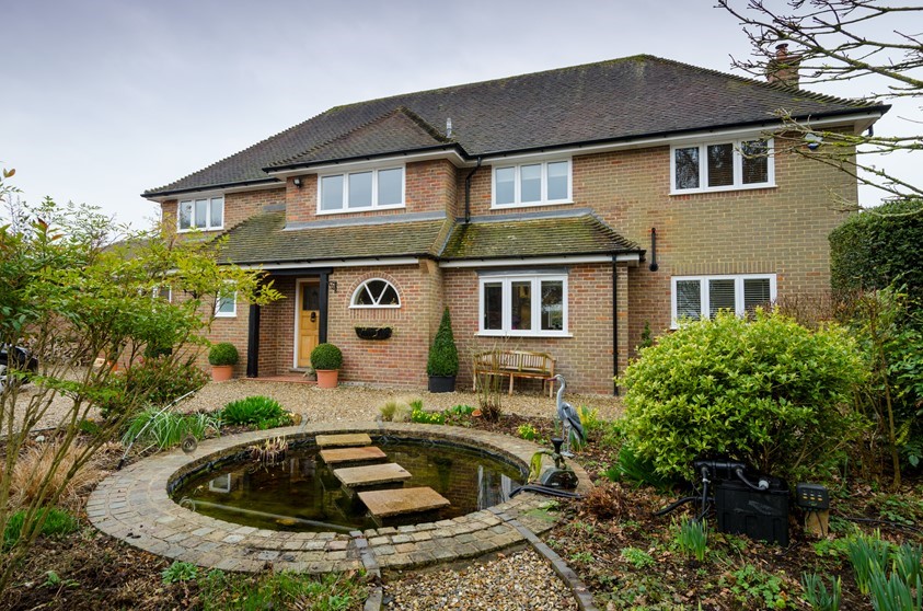 An exterior shot of the house looking over a pond with stepping stones - showcasing Origin's windows