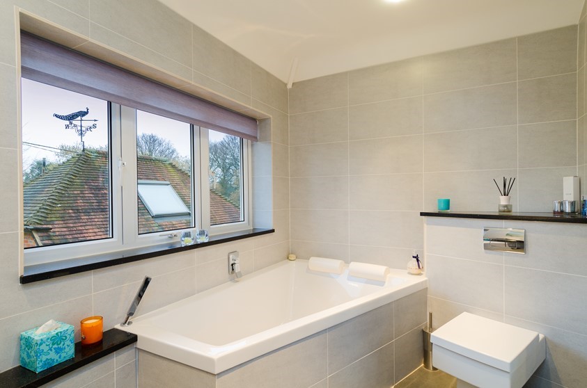 An internal view of a closed bathroom windows and blind