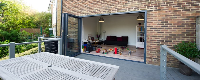 Folding doors pulled wide open providing a glimpse of a room with gym equipment and children's toys