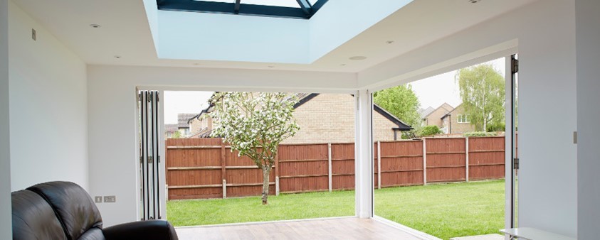 Looking out of a garden room through open folding doors that cover two walls