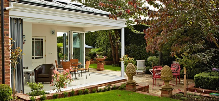 The view from the garden of a beautiful garden room, with folding doors fully opened up