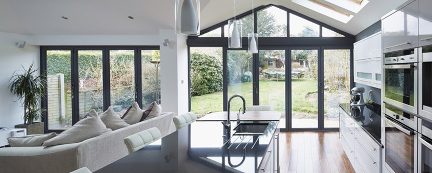 A large, modern, open plan kitchen and living area with large glass folding doors looking out to the garden