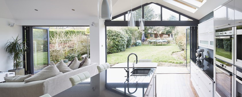 A large, bright, open plan kitchen and living area with large glass folding doors opening out to the garden