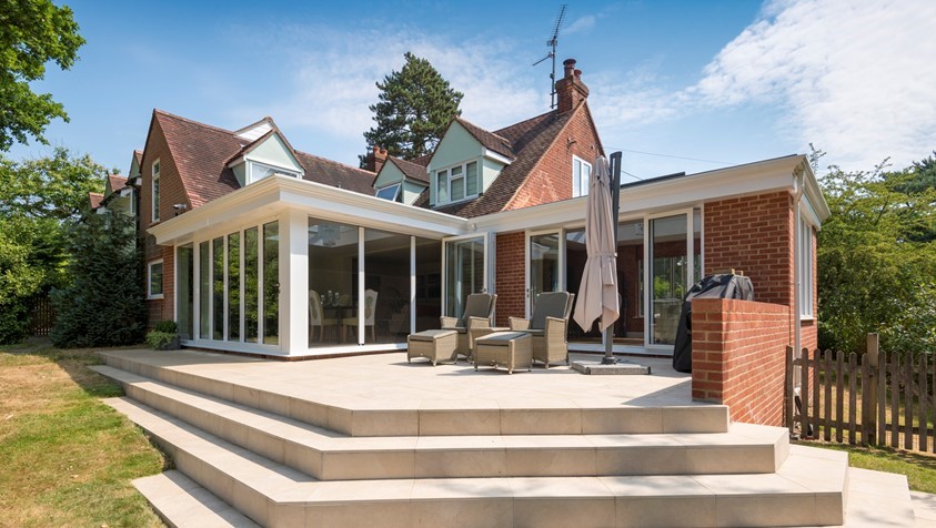 Side outside view of large house looking into the garden showing off white bifold doors