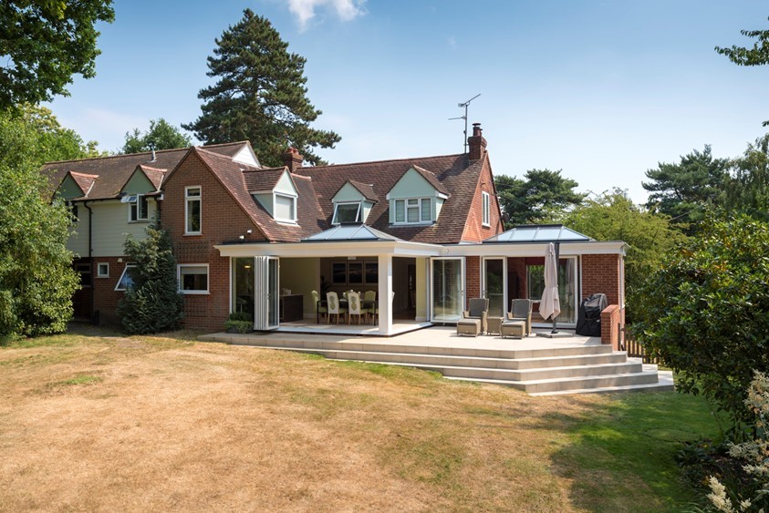 Landscape photo of the side of a house with white bifold door extension connected