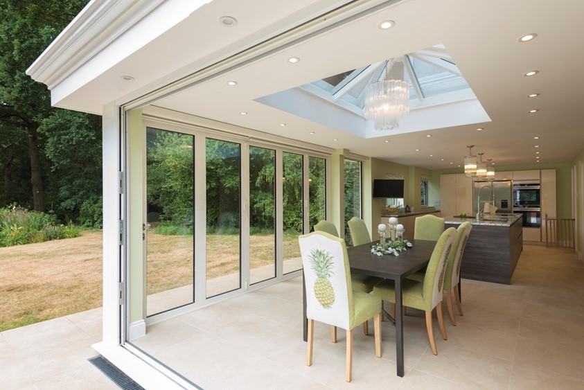 Inside of extension showing a set of chairs around a table with a open bifold door behind