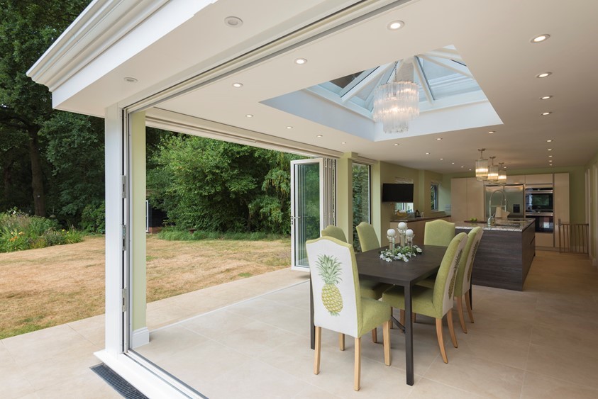 Inside of extension showing a set of chairs around a table with a open bifold door behind