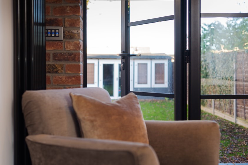 Cream chair in the corner of the room looking out through bifold doors to a garden