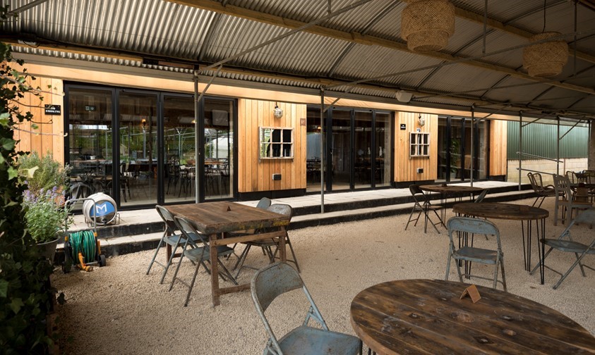 Outdoor dining tables sheltered by umbrellas placed on the outside of the bifold doors