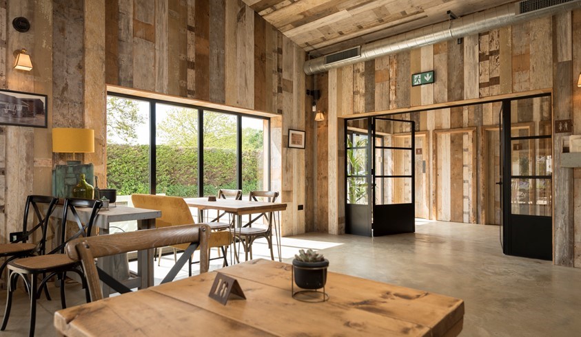 Inside a cafe with tables looking out onto a farm through bifold doors