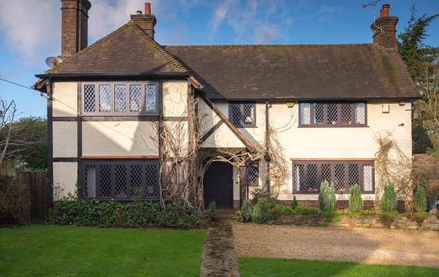 Outdoor view of a old house with vines growing outside and a car parked outside